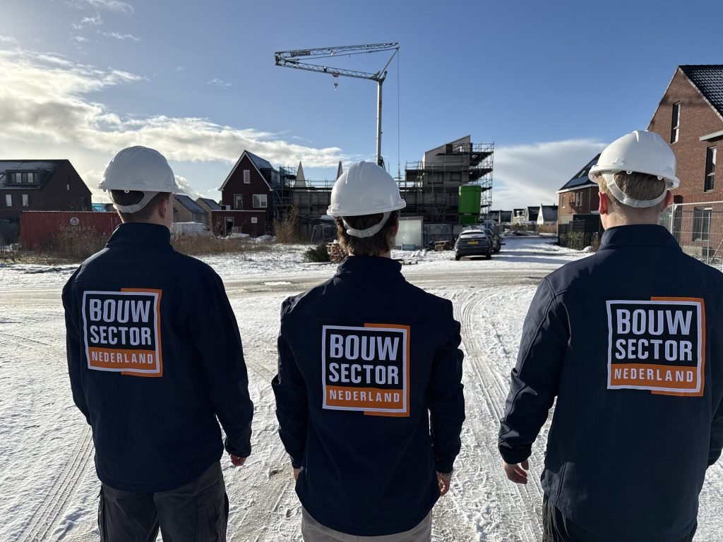 Vakmensen van Bouwsector Nederland met bouwhelm op een besneeuwde weg met bakstenen woningen en een kraan